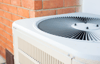 Outdoor HVAC condenser unit with a reinforced polypropylene fan grille protecting the fan assembly from debris and accidental contact.