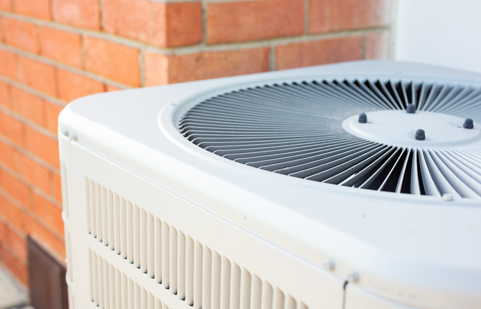 Outdoor HVAC condenser unit with a reinforced polypropylene fan grille protecting the fan assembly from debris and accidental contact.